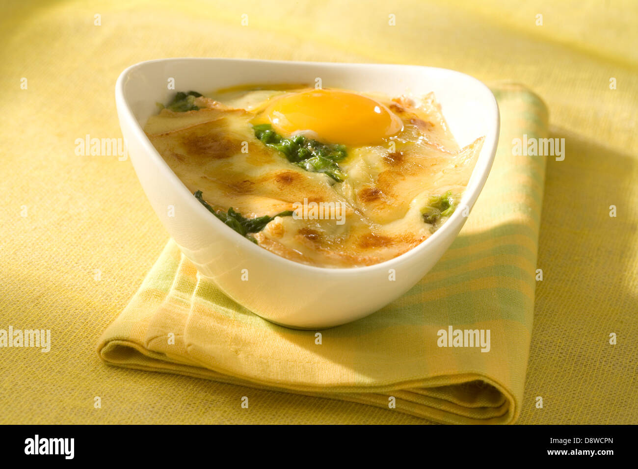 Gebackenes Ei mit Spinat und Raclette-Käse Stockfoto