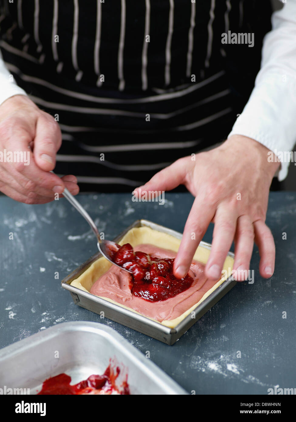 Der Konditor-Creme Inverkehrbringen Erdbeeren-Marmelade in der Mitte des Kuchens Stockfoto