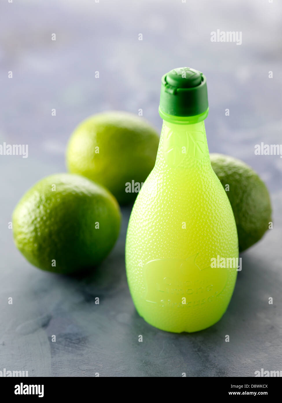 Kleine Flasche Limettensaft und Limetten Stockfoto