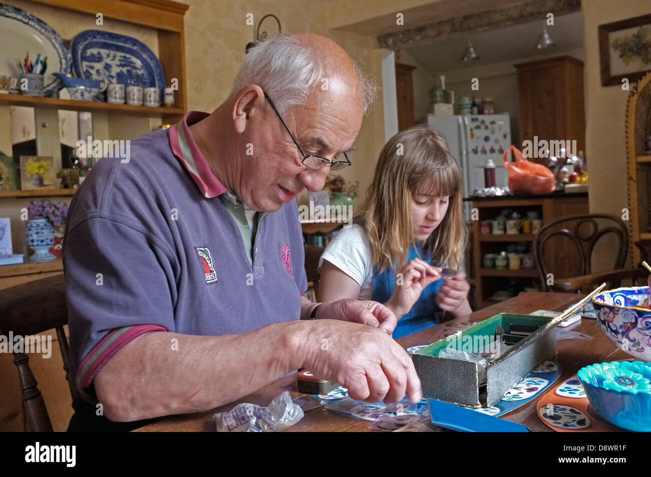 Ein Großvater und seine Enkelin Blick durch eine Schachtel mit alten Münzen Stockfoto