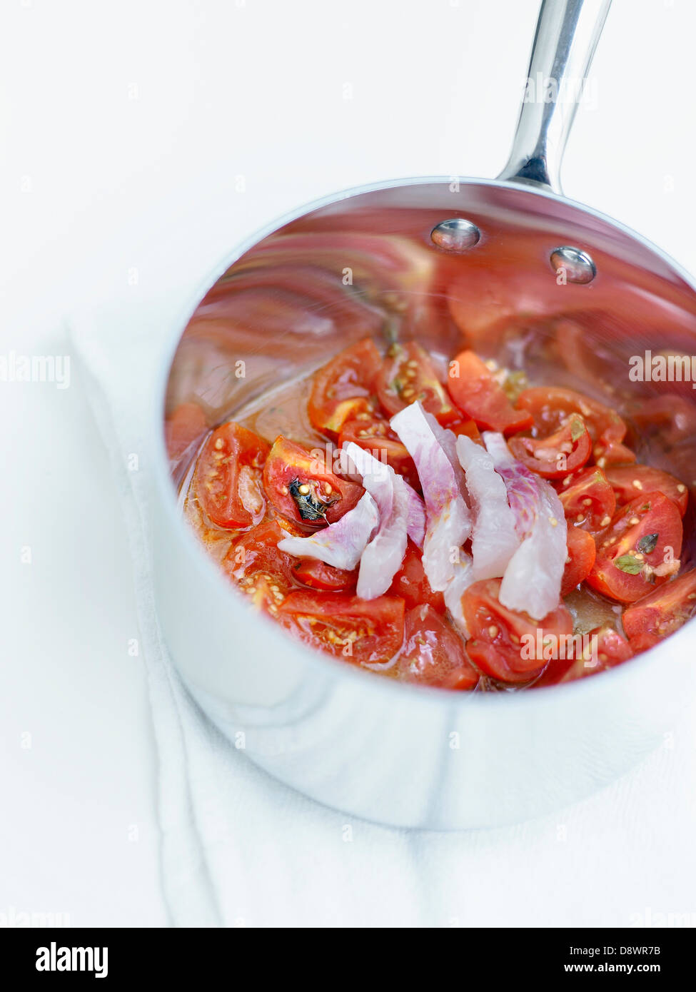 Tomaten und Oregano mit dünn geschnittene rohe rote Meerbarben in einen Topf geben Stockfoto