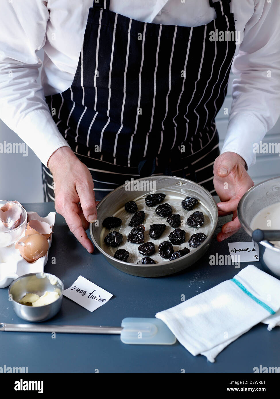 Platzieren die Pflaumen in die Backform Stockfoto