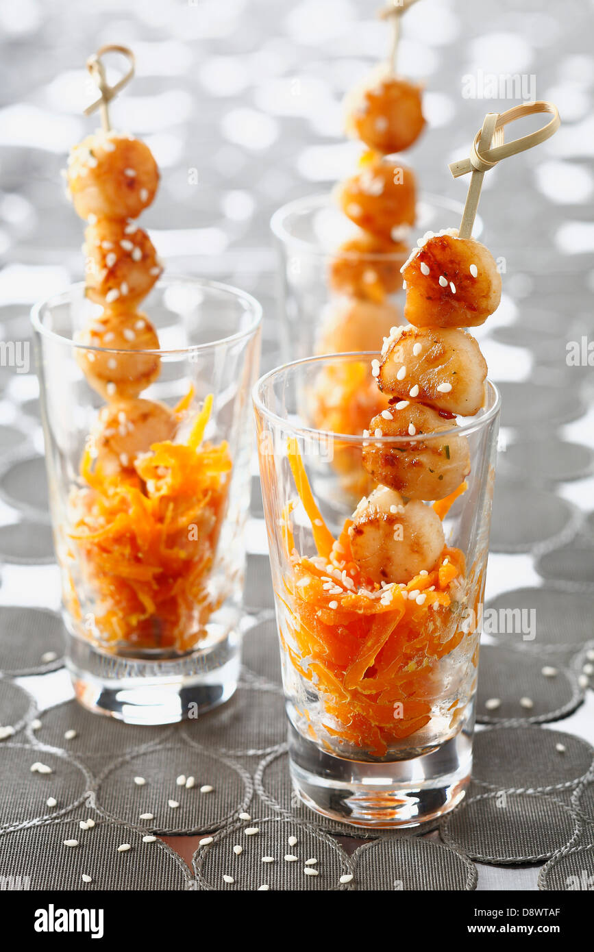 Jakobsmuschel-Spieße mit geriebenen Karotten und Sesam Stockfoto
