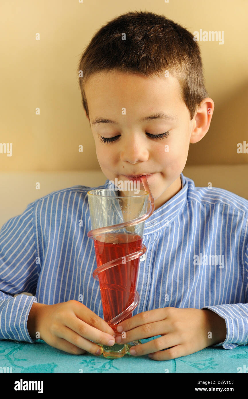 Kleiner Junge Erdbeere herzlich mit einem Strohhalm trinken Stockfoto