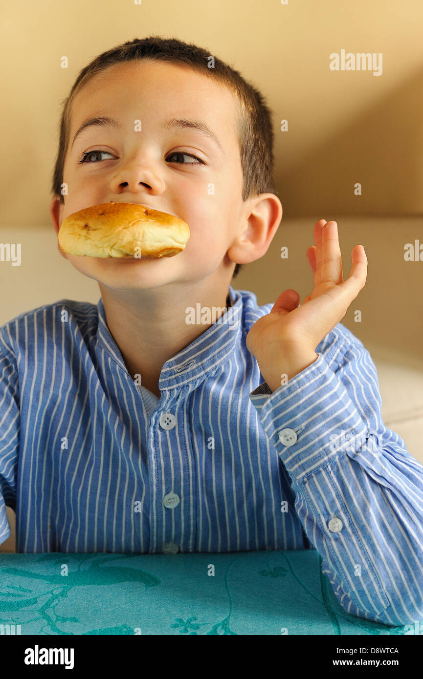 Kleiner Junge eine Brötchen zu essen Stockfoto