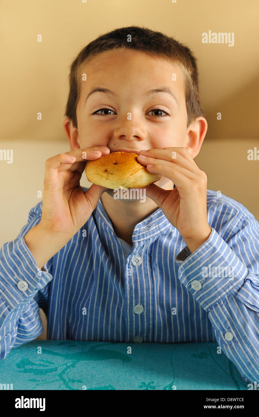 Kleiner Junge eine Brötchen zu essen Stockfoto