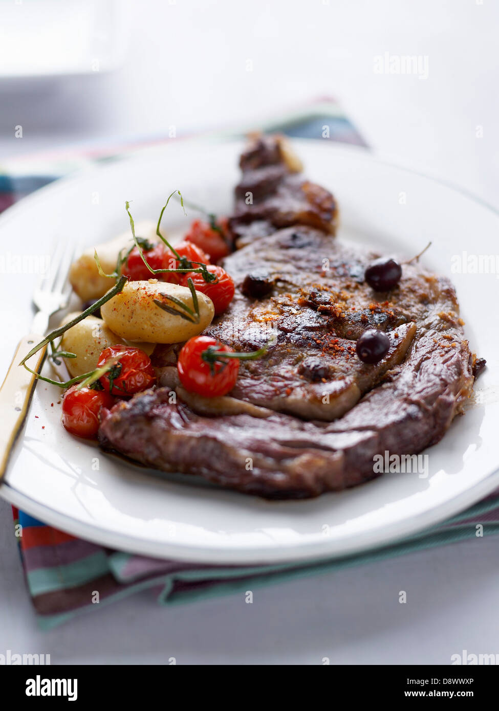Gegrilltes Rindfleisch Entrecôte mit Oliven, Kirschtomaten und Ratte-Kartoffeln Stockfoto