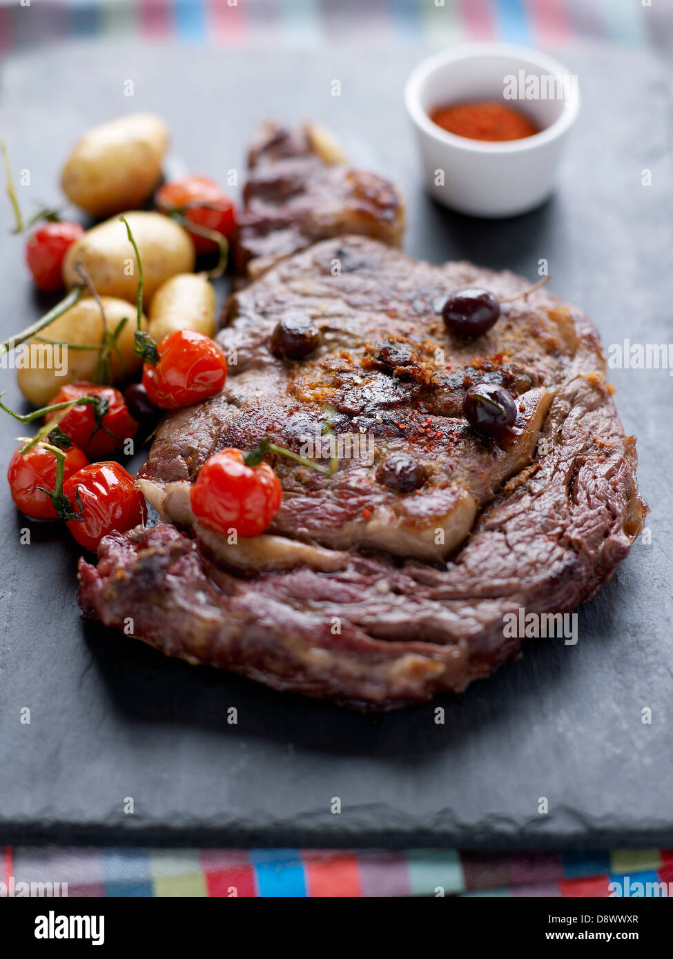 Gegrilltes Rindfleisch Entrecôte mit Oliven, Kirschtomaten und Ratte-Kartoffeln Stockfoto