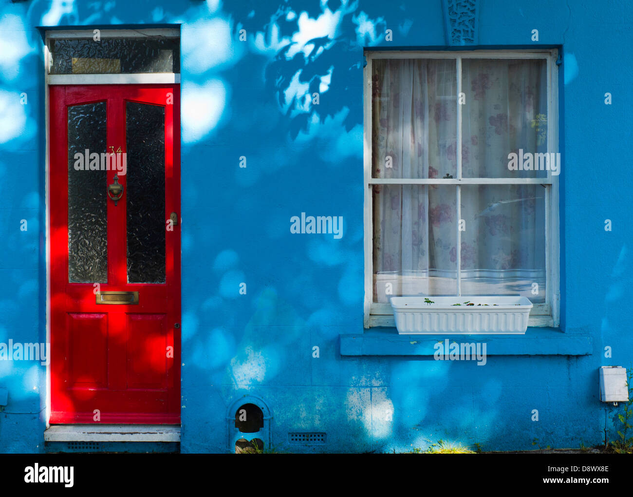 Rote Tür im blauen Haus, gefleckten Licht, Brighton, UK Stockfoto