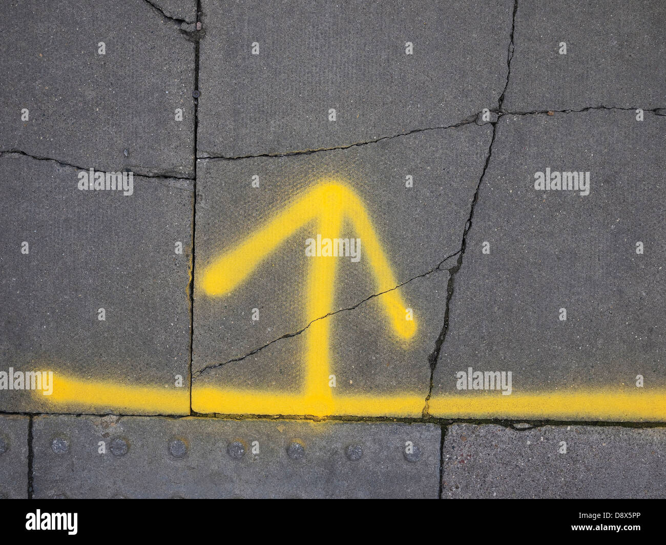 gelb lackierte Pfeil auf grauen Asphalt Stockfoto