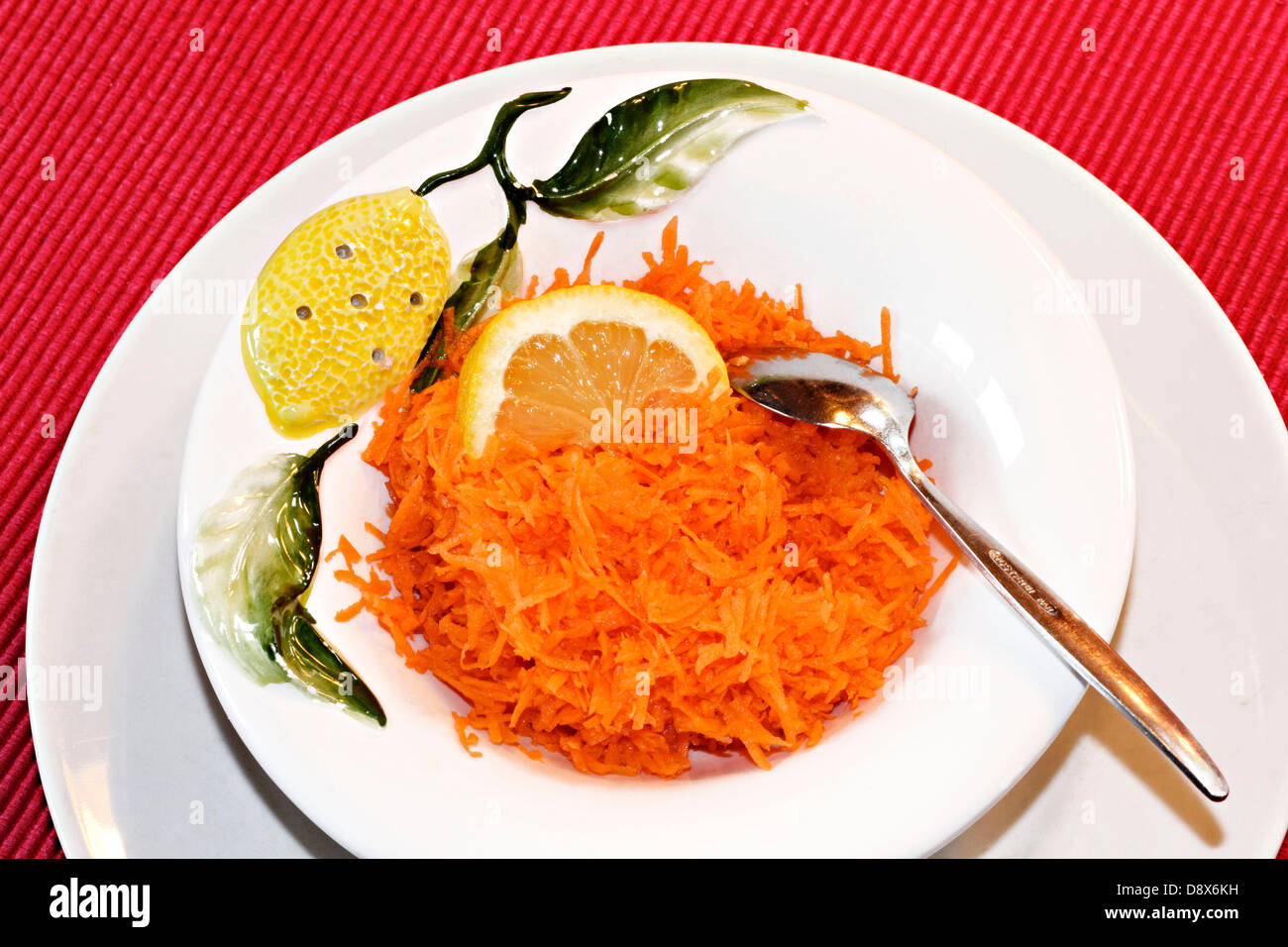 Geriebene Karotten in Schüssel mit Zitronenscheibe Stockfoto