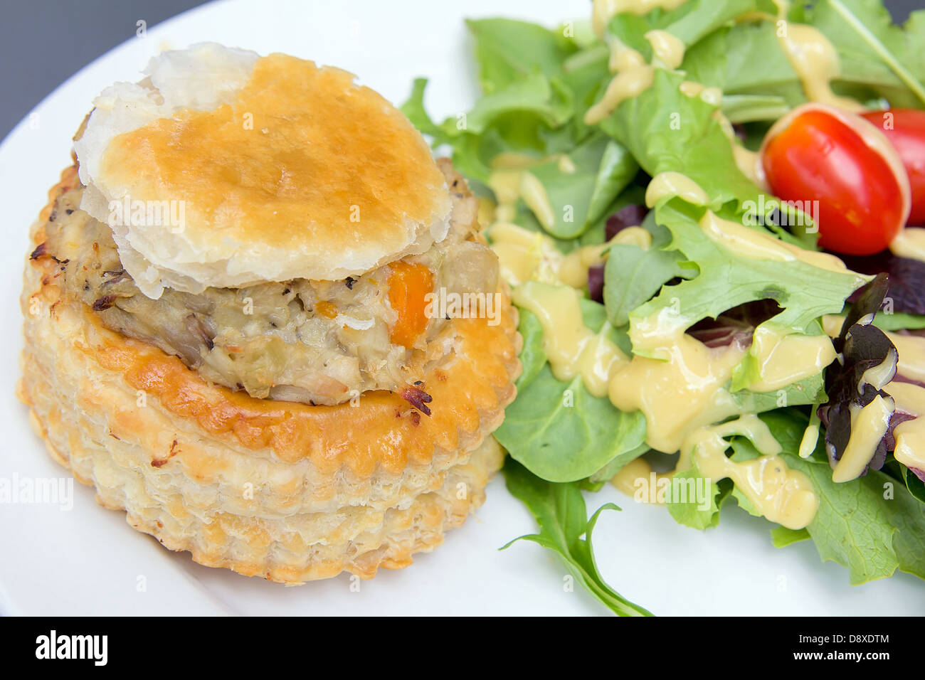 Hühnerpastete mit grünem Blattgemüse Tomaten und Salat-Dressing-Nahaufnahme Stockfoto