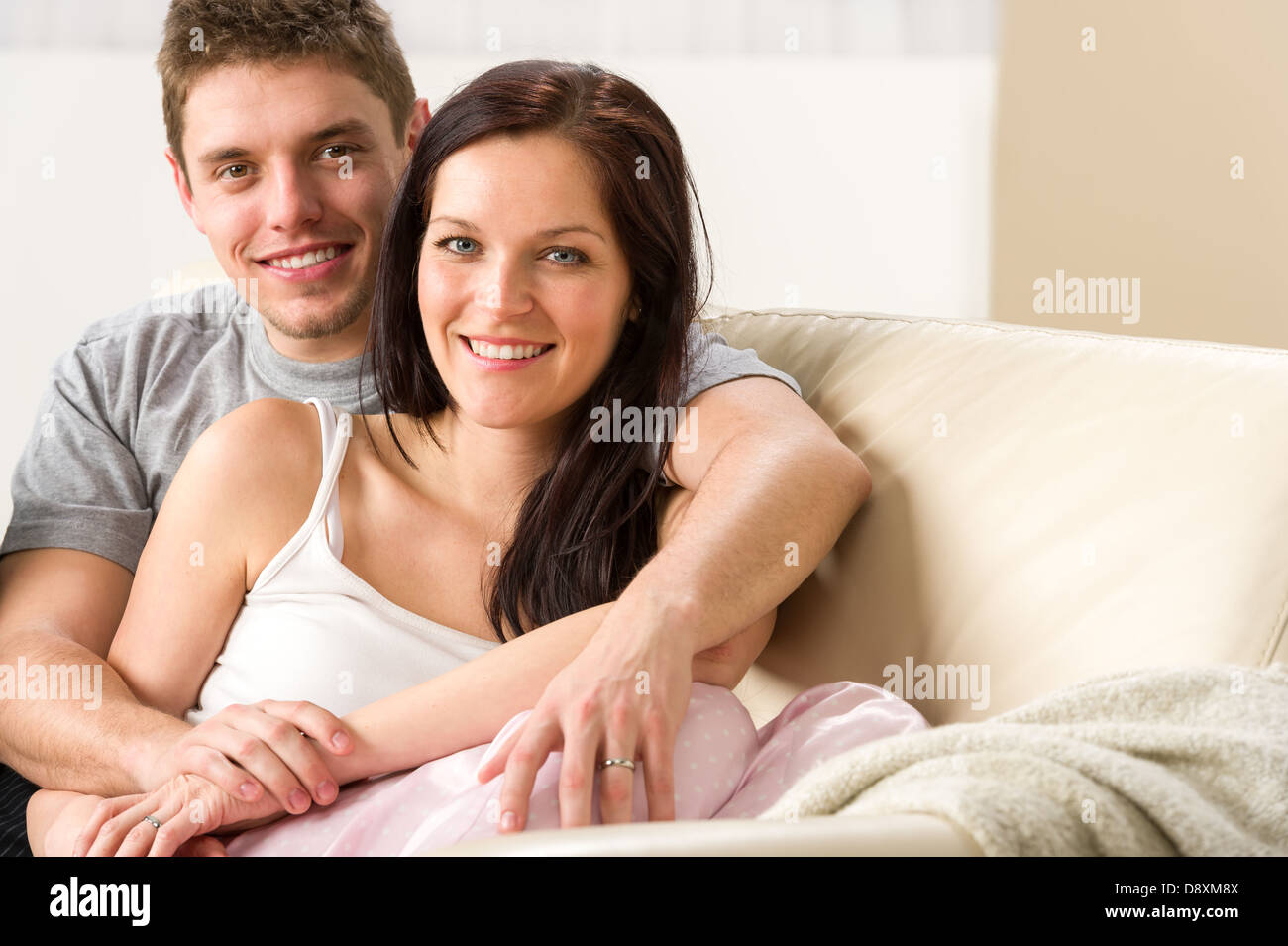 Unbeschwertes junges Paar umarmen einander auf couch Stockfoto