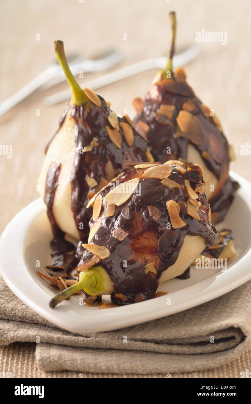 Geschmorte Birnen mit Schokoladensauce und dünn geschnittenen Mandeln Stockfoto