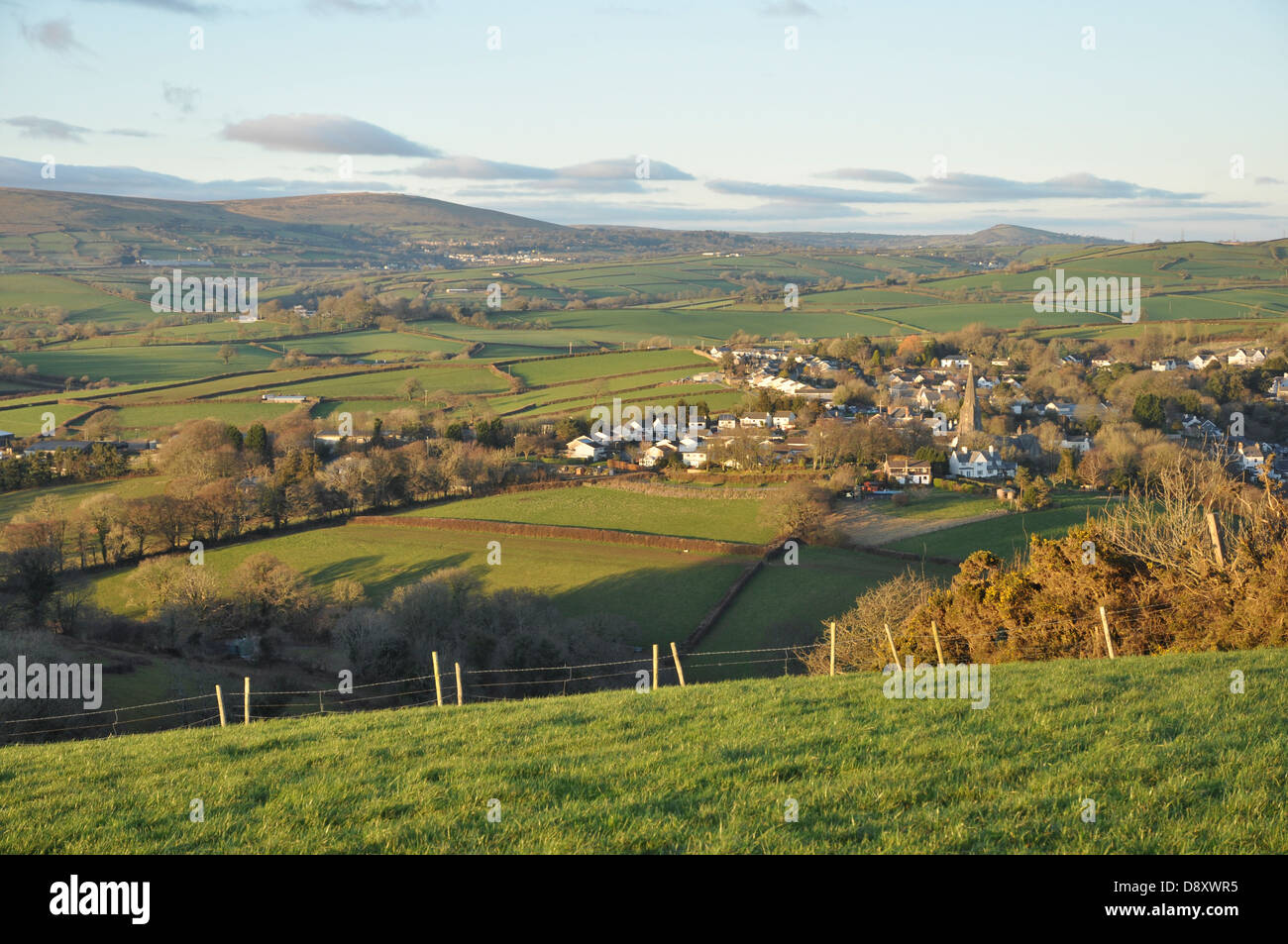 Blick über Modbury auf Dartmoor. Bake, Western, Ugborough Leuchtfeuer und Brent Hill im Hintergrund sichtbar. Kirche im Vordergrund Stockfoto