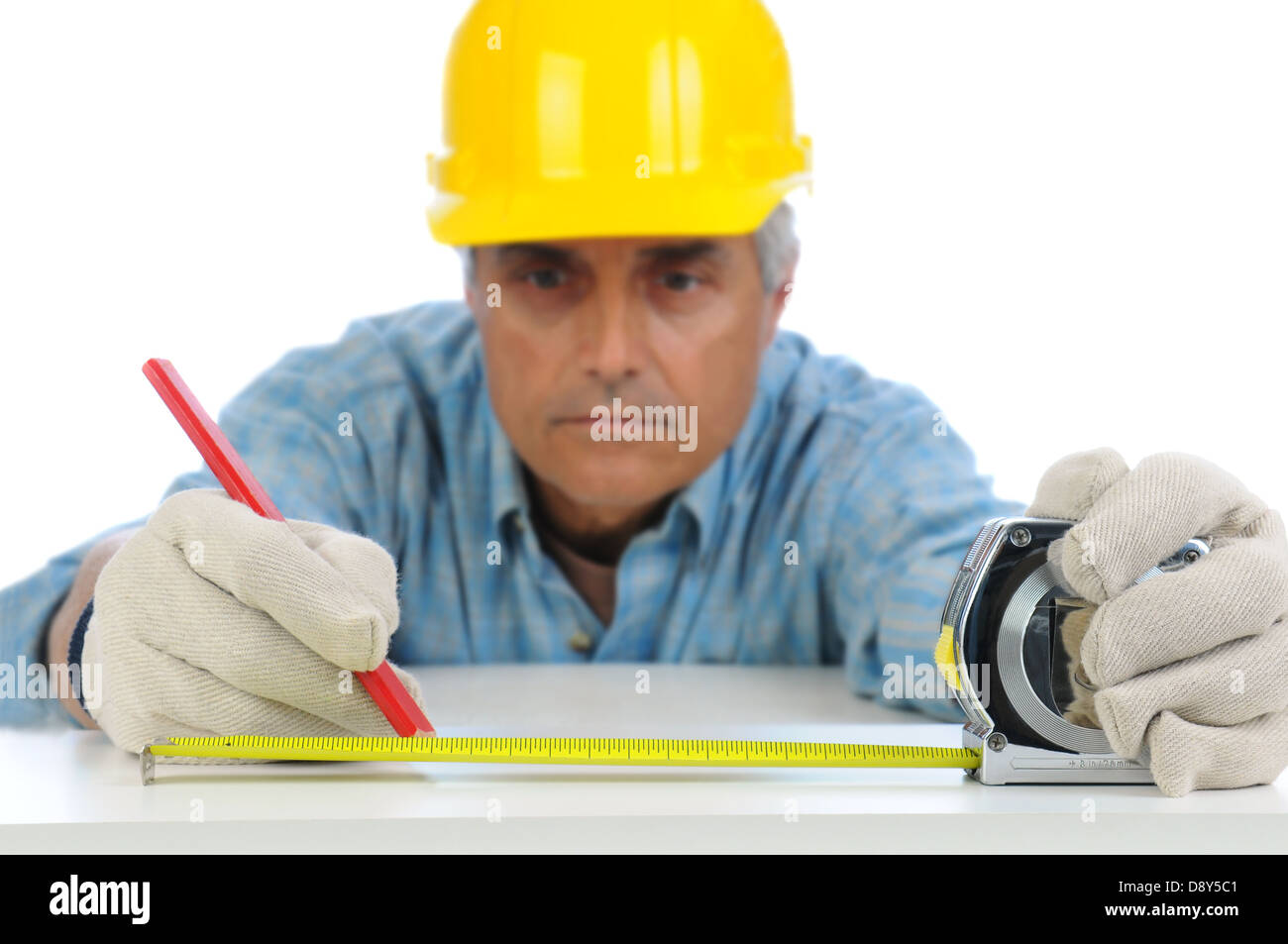 Nahaufnahme eines Bauarbeiters im harten Hut mit einem Maßband, um Schnittverlauf auf einem Brett zu markieren. Stockfoto