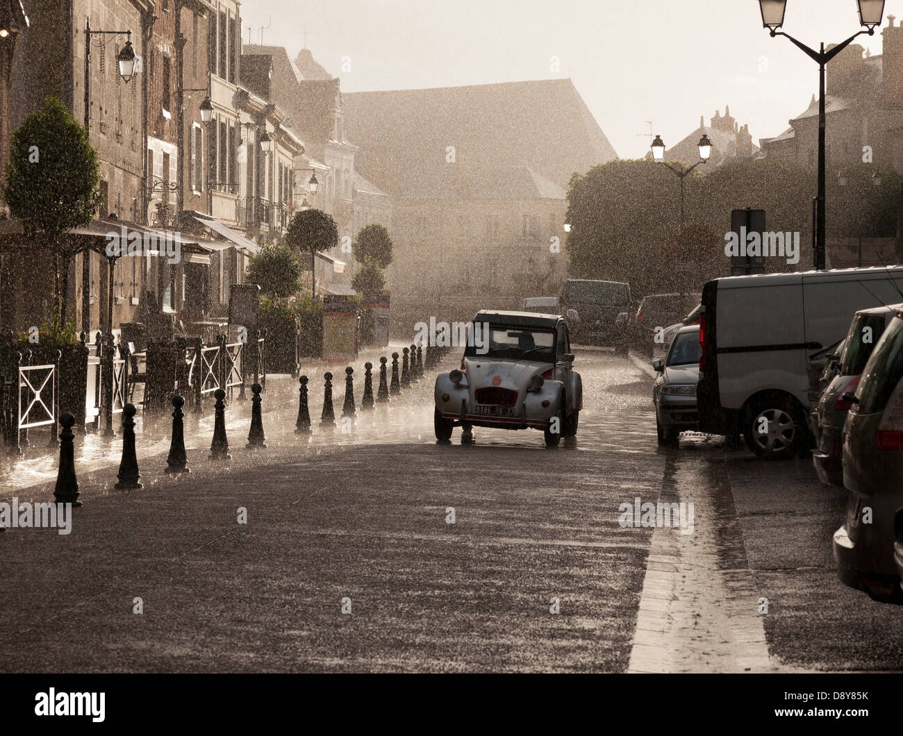Französische Straße Szene. Klassische Citroen 2CV fahren entlang einer Straße bei starkem Regen, Ambroise Indre et Loire Frankreich Europa Stockfoto