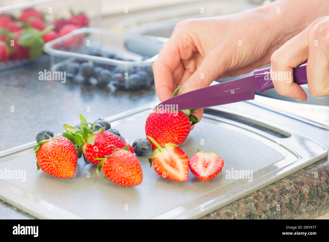 Frau Vorbereitung / schneiden, Erdbeeren und Heidelbeeren Stockfoto