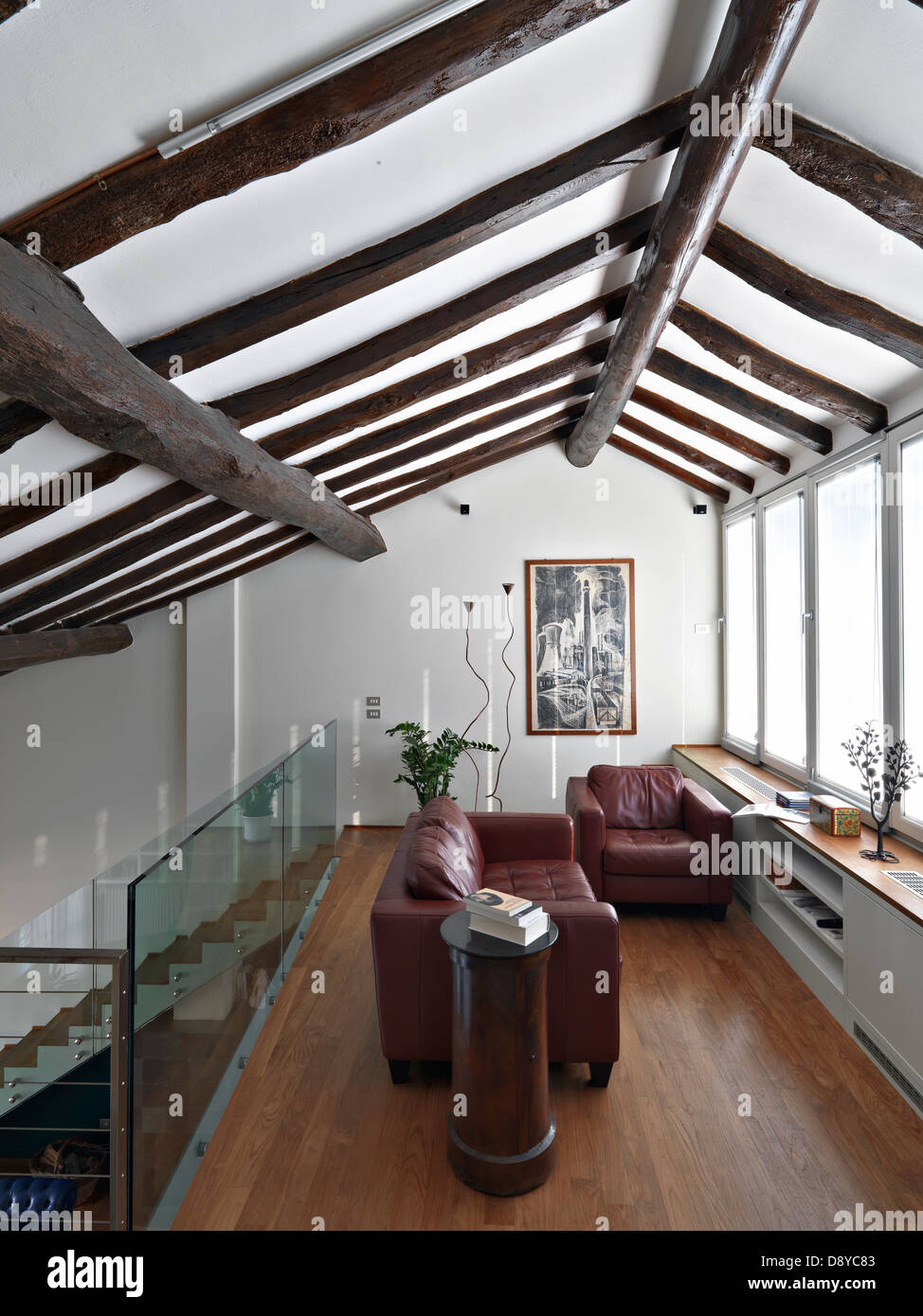 rotes Ledersofa im Dachgeschoss mit Holzfußboden und Holzdecke Stockfoto