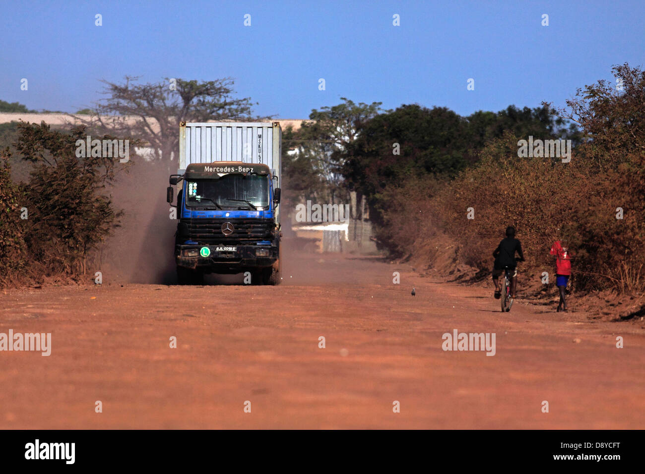 Gambia LKW Transport Seecontainer auf unbefestigten roter Feldweg zum Terminal auf der Bund-Straße Stockfoto