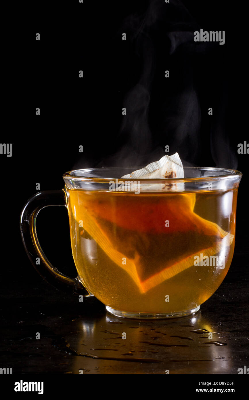 heiße Tasse Tee serviert auf einer dunklen Umgebung mit Dampf und ein Anis Sterne schweben mit den Teebeutel Stockfoto