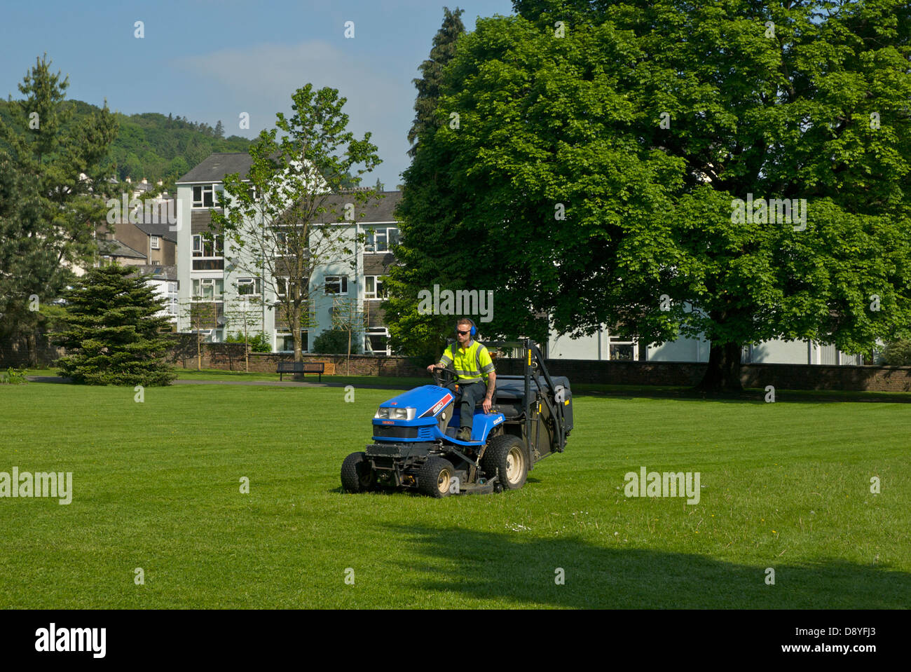 Des Rates Mitarbeiter mit Reiten-auf Rasenmäher, Mähen im kleinen Park, Kendal, Cumbria, England UK Stockfoto