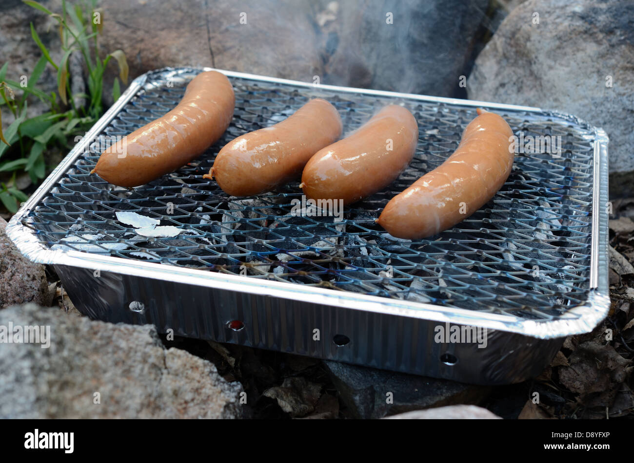 Würste Kochen auf einem Einweg-Grill im freien Stockfoto