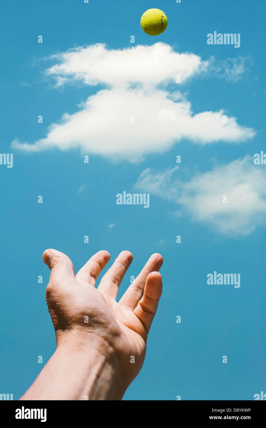 Hand des Mannes werfen Tennisball vor blauem Himmel Stockfoto