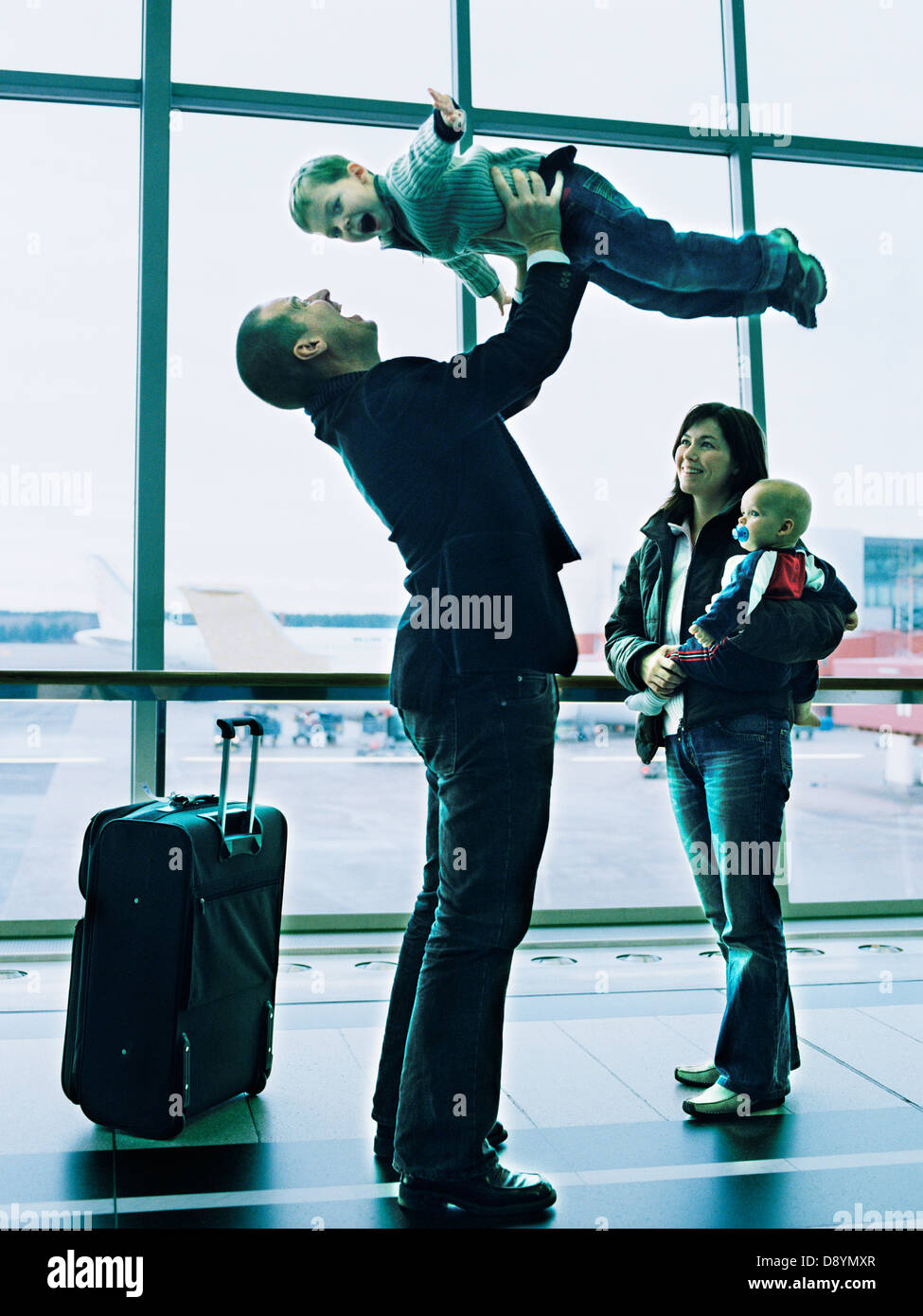 Freundliche Familie auf dem Flughafen und Abhaltung Sohn Mann Stockfoto