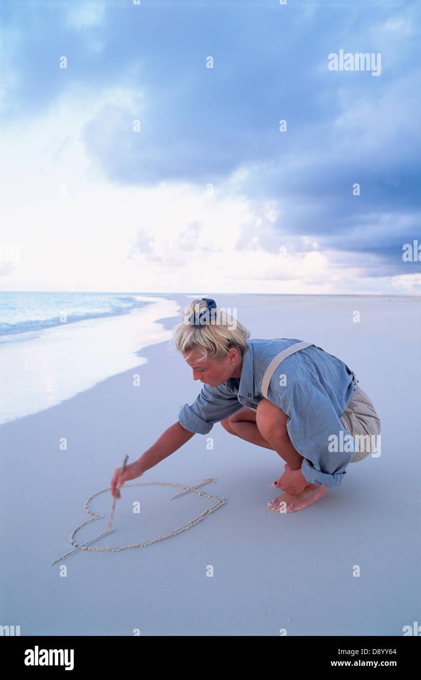 Eine Frau zeichnen ein Herz in den Sand. Stockfoto