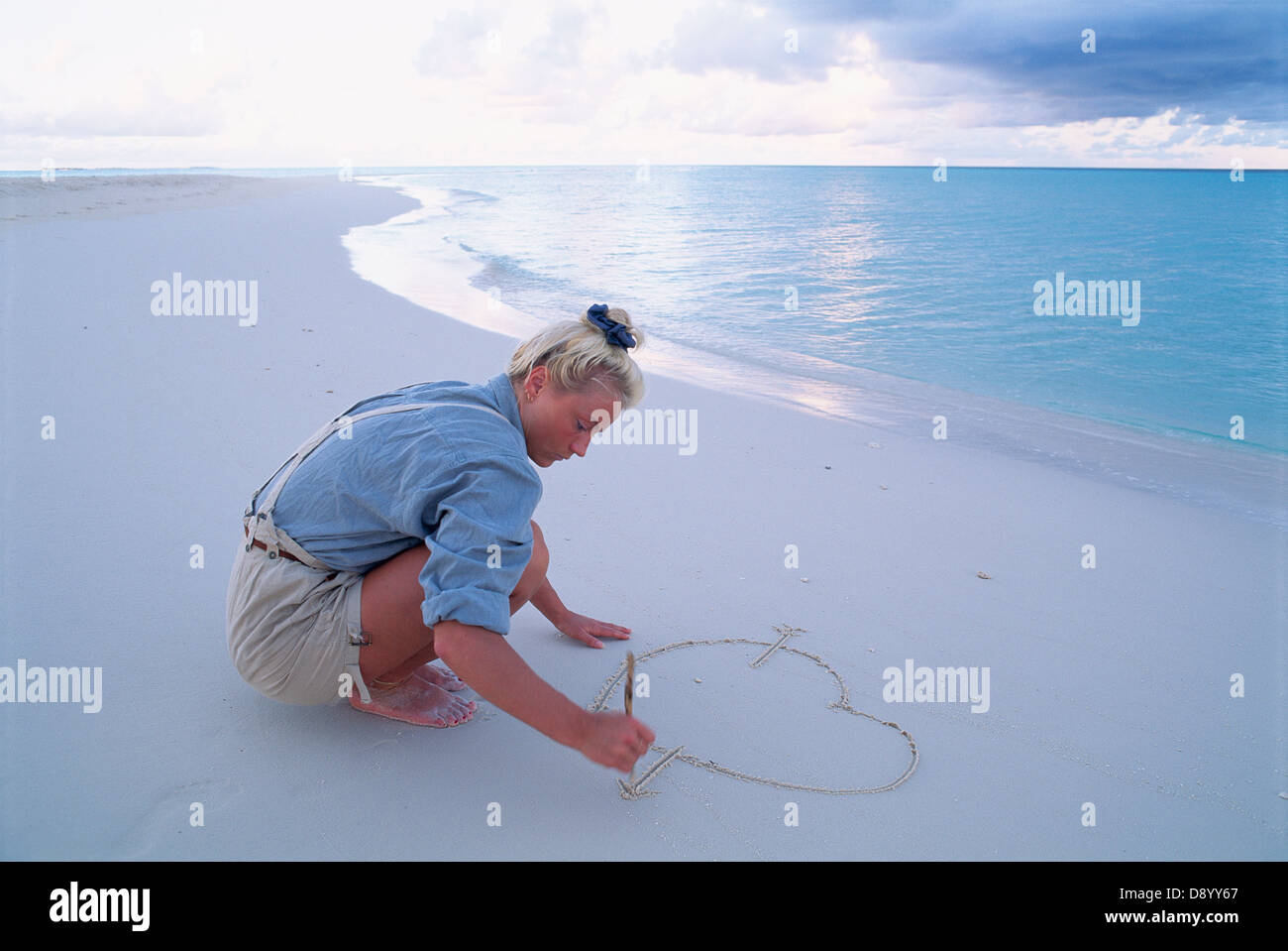 Eine Frau zeichnen ein Herz in den Sand. Stockfoto
