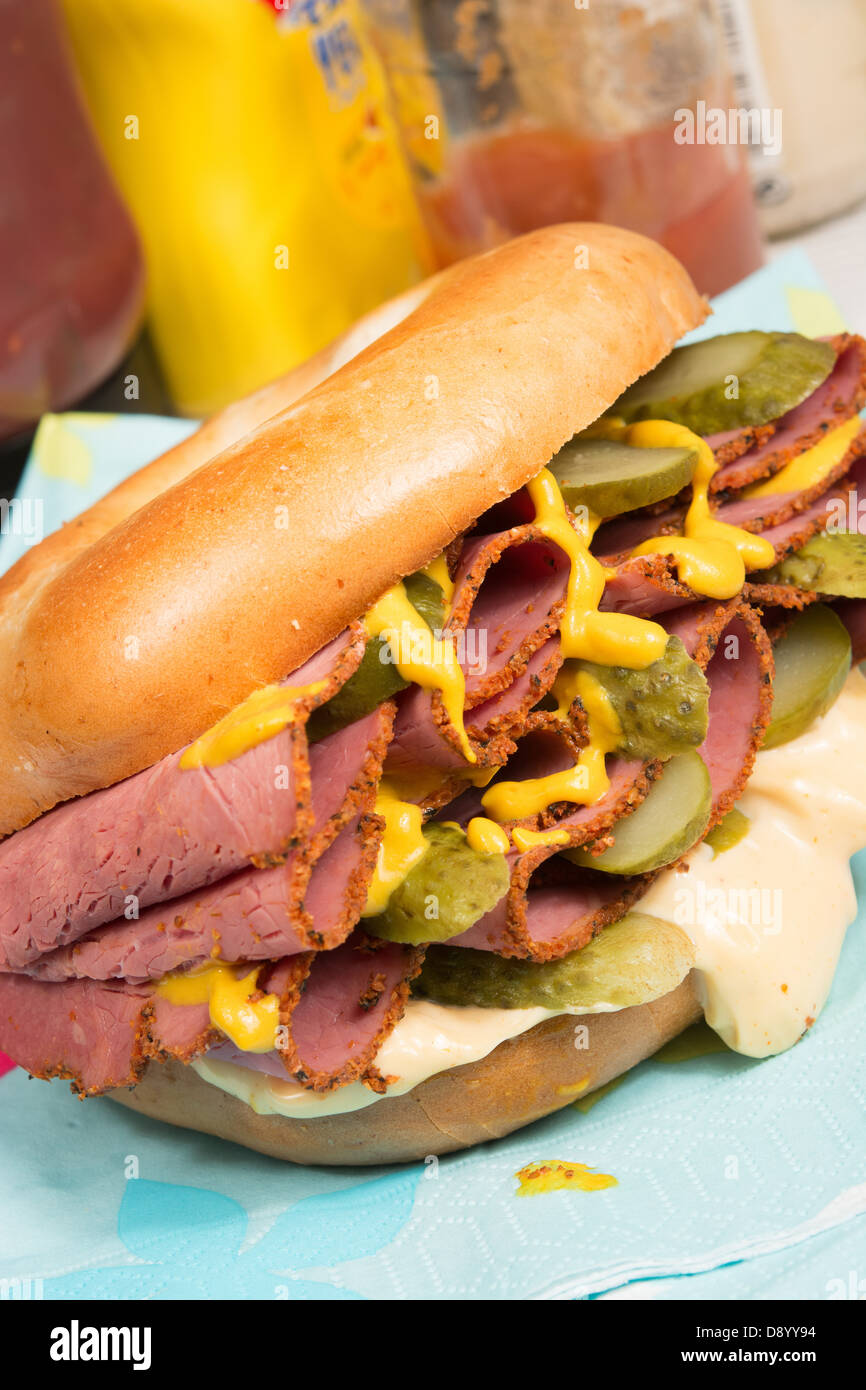 Ein schlichter Bagel gefüllt mit Pastrami, in Scheiben geschnittenen Gurken, Senf und Chili-Mayonnaise. Stockfoto