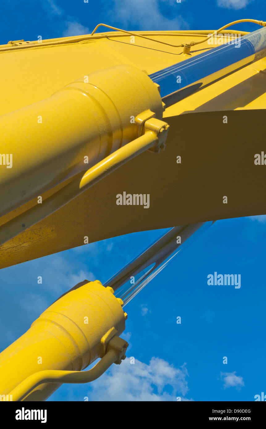 Gelbe Baggerarm und hydraulische Kolben schließen Ansicht gegen blauen Himmel Stockfoto