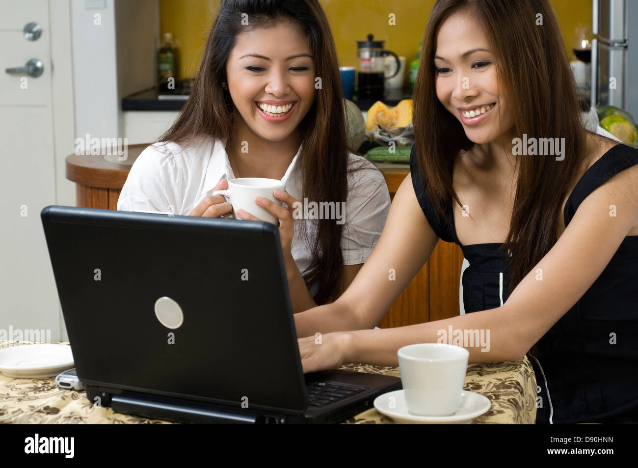 Philippinen, zwei junge Frauen, die Arbeiten am Laptop in Küche Stockfoto
