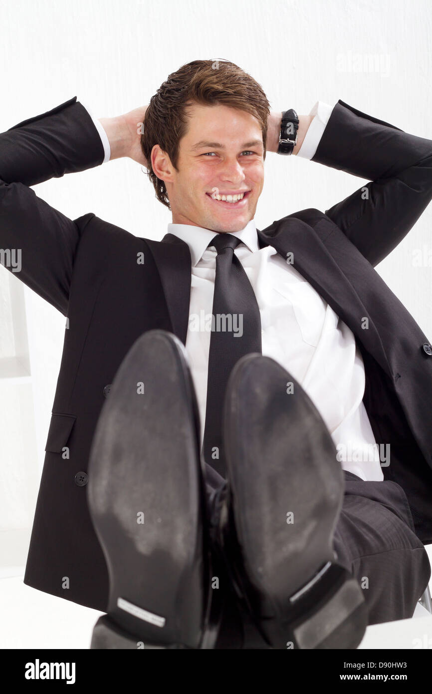 entspannte junger Geschäftsmann mit Armen hinter dem Kopf Stockfoto