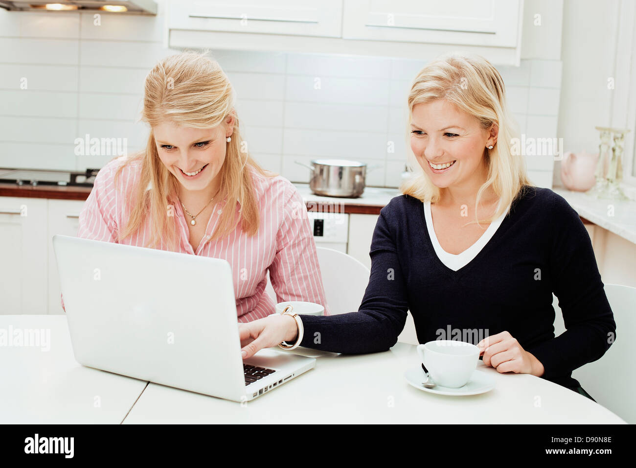 Zwei junge Frauen mit Laptop in der Küche Stockfoto