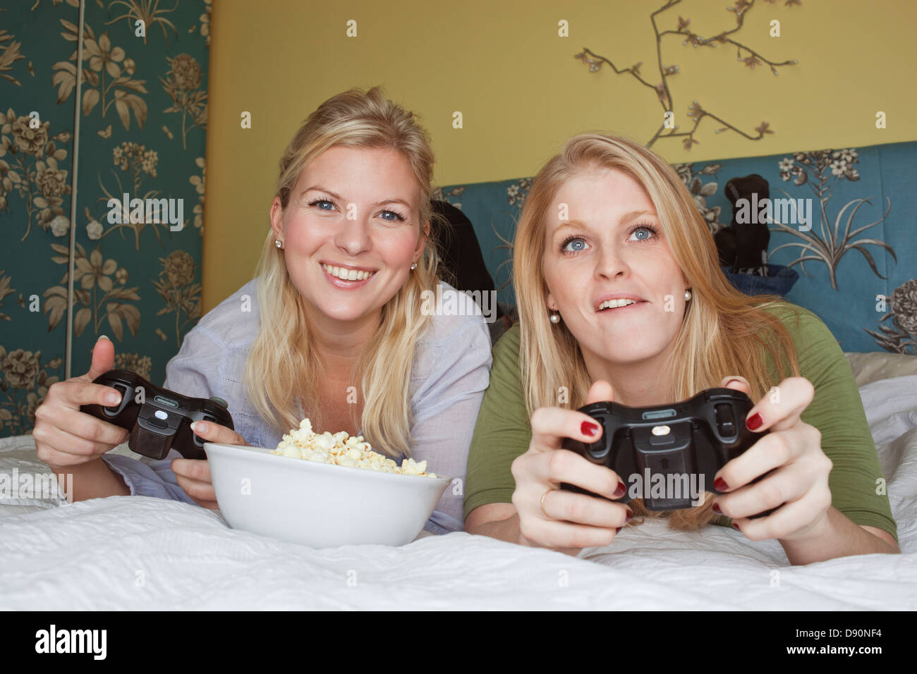 Zwei junge Frauen spielen Videospiel im Schlafzimmer Stockfoto