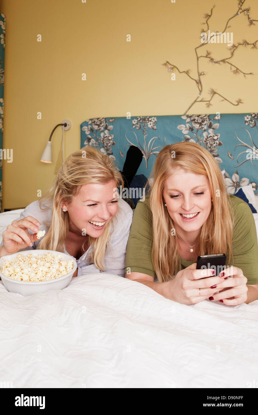 Zwei junge Frauen mit Handy im Schlafzimmer Stockfoto