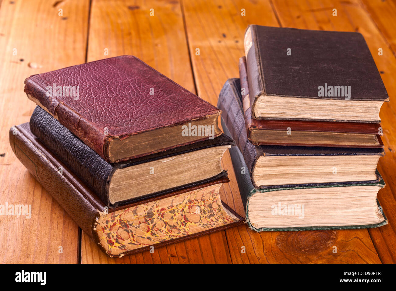 Alte Bücher 0n rustikalen Kiefer Tisch - Stapel alter Bücher auf einem rustikalen Holztisch. Stockfoto