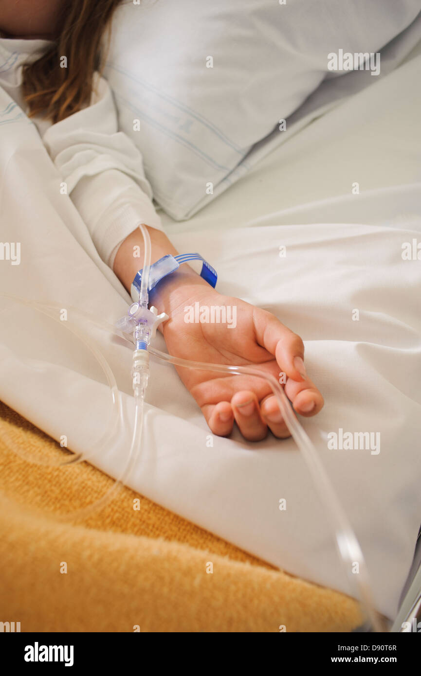 Mädchen auf Krankenbett liegend mit Tropf am arm Stockfoto