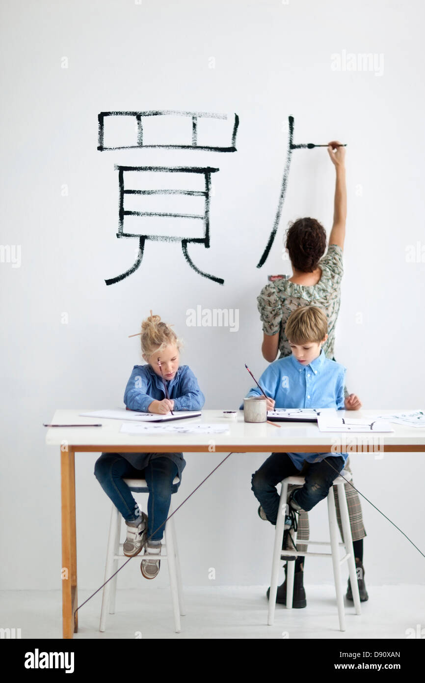 Jungen und Mädchen mit weiblichen Lehrer während des Unterrichts Kunst Malerei Stockfoto