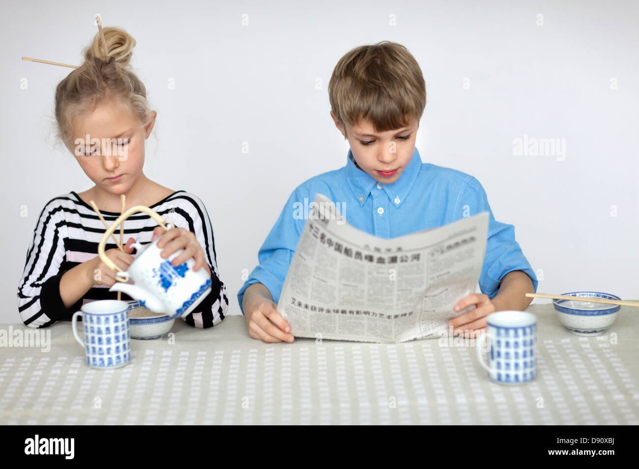 Mädchen Gießen Tee und junge liest Zeitung Stockfoto
