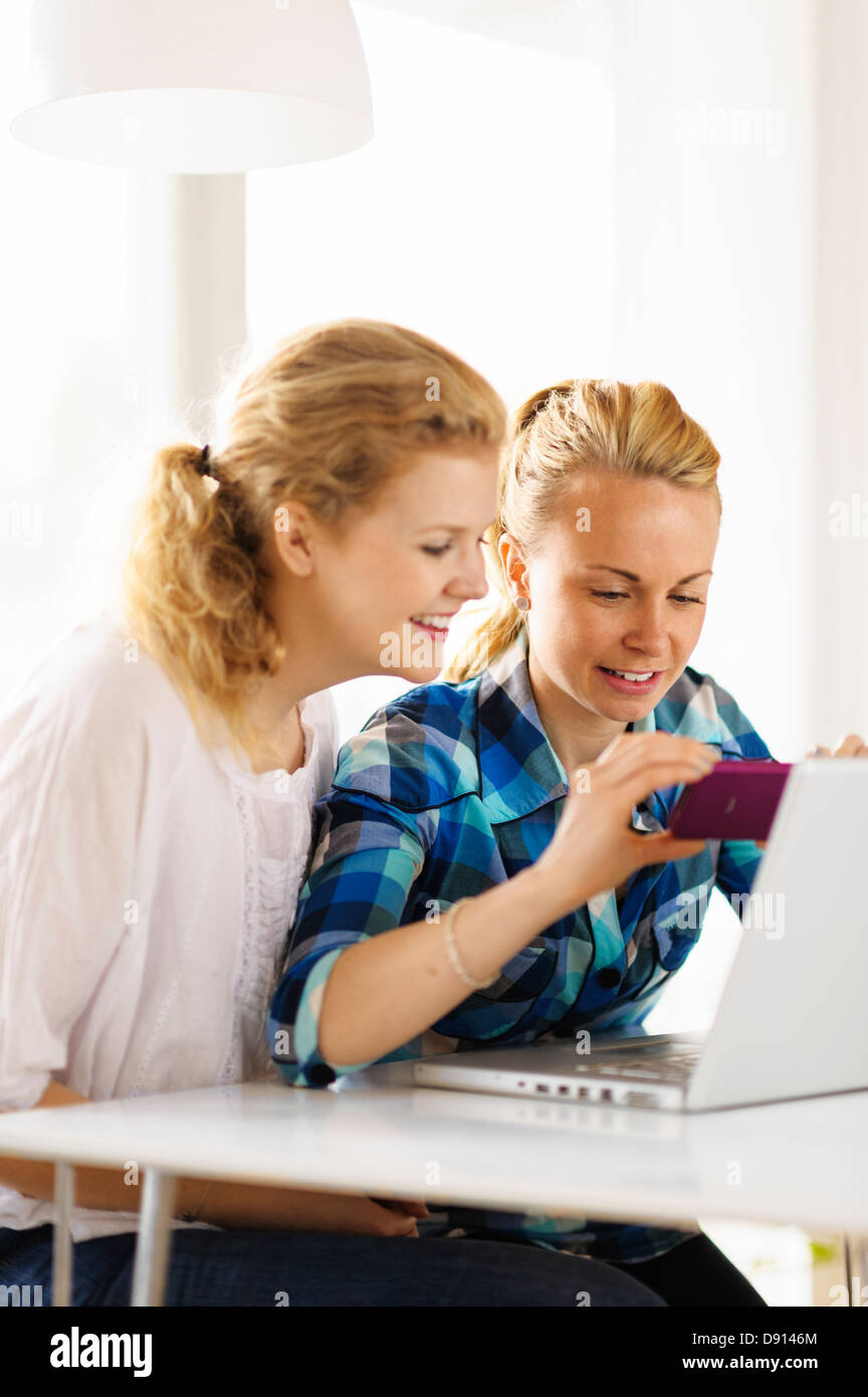 Zwei junge Frauen mit Laptop mit Handy Stockfoto