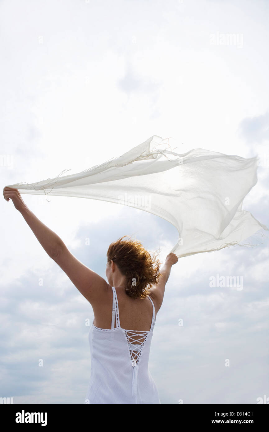 Eine Frau hält einen weißen Schal im Wind am Meer, Schweden. Stockfoto