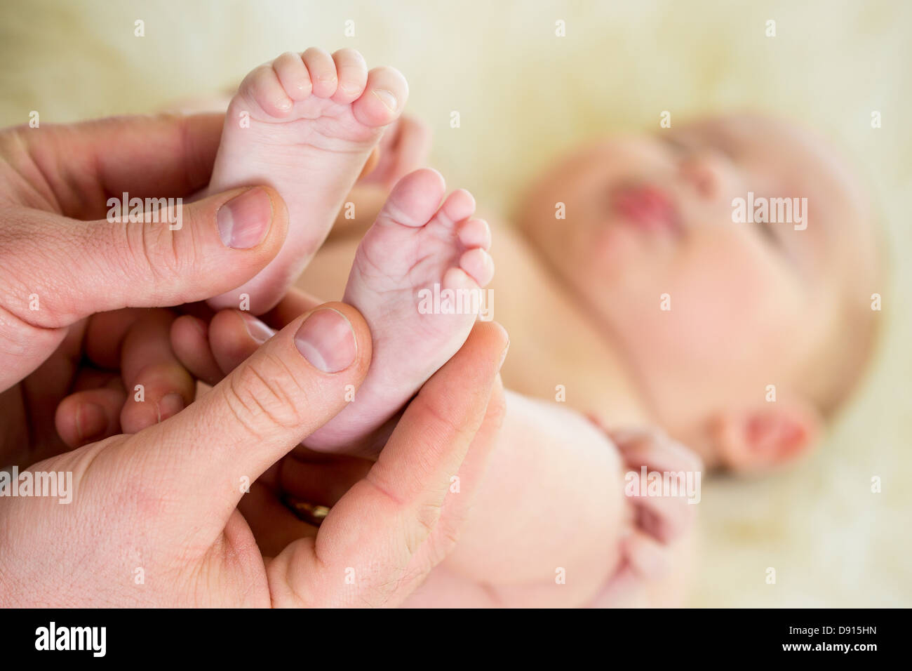 männliche Hände massieren Füße kleine Babys Stockfoto