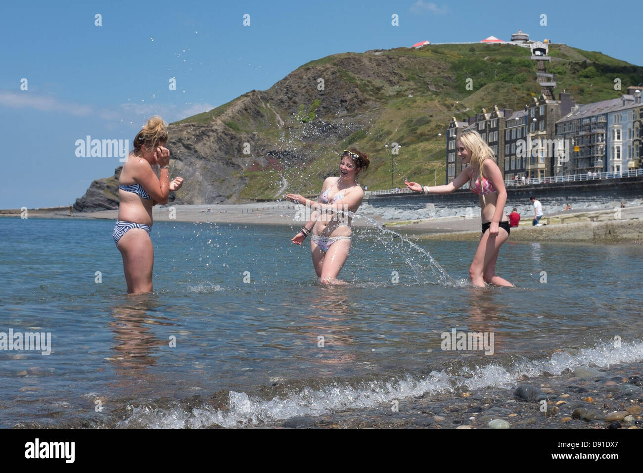 Aberystwyth Wales UK, Samstag, 8. Juni 2013.   Drei junge Frauen Paddeln im Meer genießen noch einen feinen Tag warmes sonniges Wetter am Strand und der Promenade in Aberystwyth an der Cardigan Bay Küste, West Wales UK.  Maximale Temperaturen für den Tag sind es voraussichtlich in den niedrigen 20er Jahren Grad Celsius Photo Credit: Keith Morris/Alamy Live-Nachrichten Stockfoto