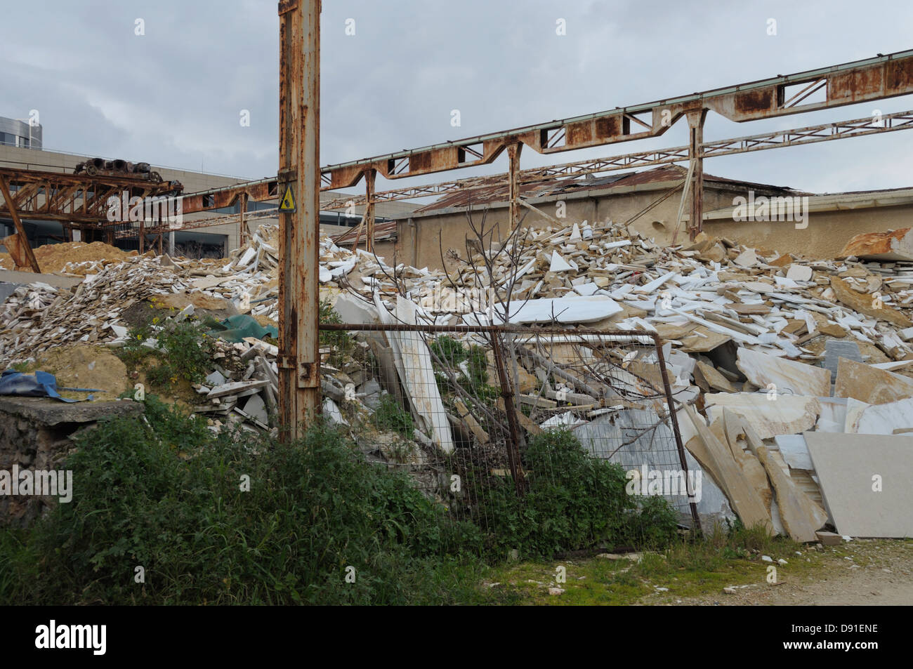 Haufen von gebrochenen Marmor und rostigen Industriemaschinen. Verlassene Fabrik Exterieur. Stockfoto
