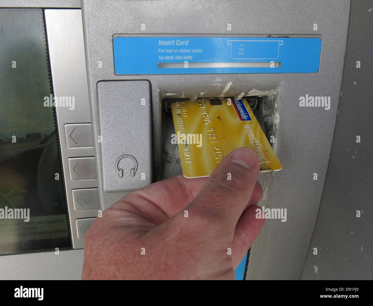 Eine Nationwide-Kontokarte in einen Geldautomaten der Genossenschaft stecken, gelb Stockfoto