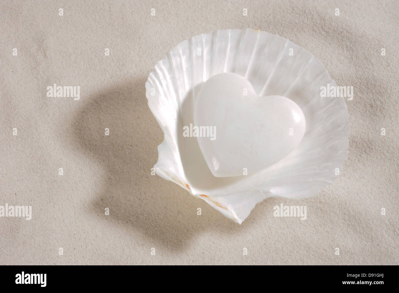 Weißes Herz in Muschel über sand Stockfoto