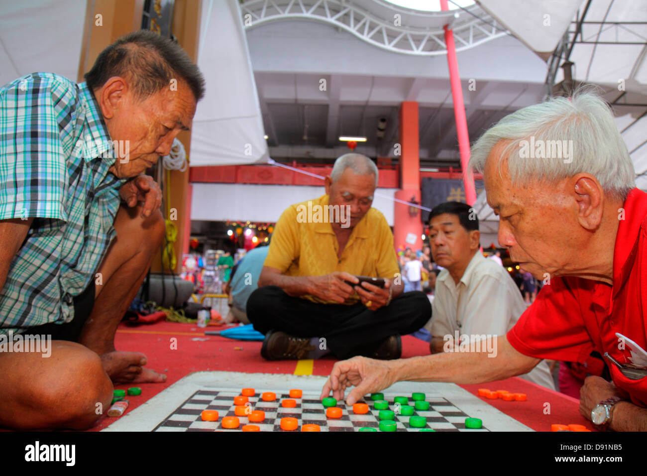 Chinatown in Singapur, asiatischer Mann, Männer, spielen, Dame, Entwürfe, Brettspiel, hanzi-Charaktere, überprüfen, Smartphone, Telefone, prüfen, ob Text gelesen wird Stockfoto